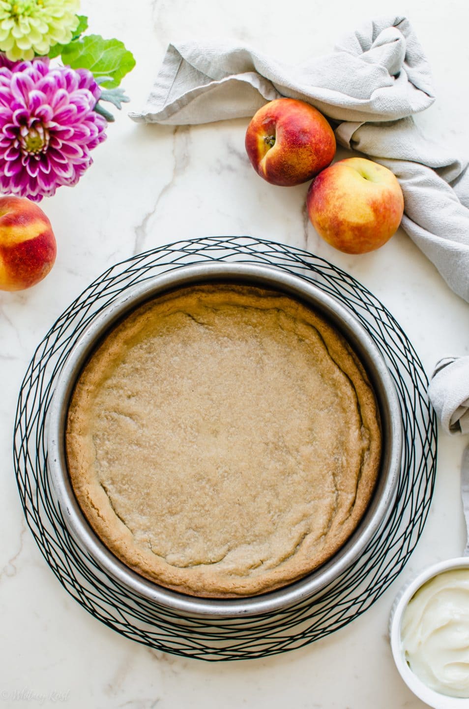 An overhead shot of a cake pan with a baked snickerdoodle cookie crust.