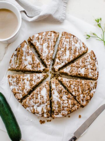 An overhead shot of a sliced zucchini coffee cake with a cup of coffee on the side.