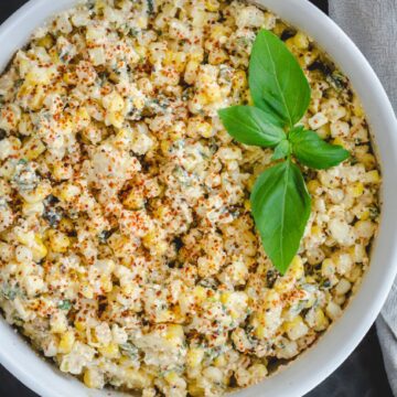 An overhead shot of a white bowl of elote roasted corn and poblano peppers.