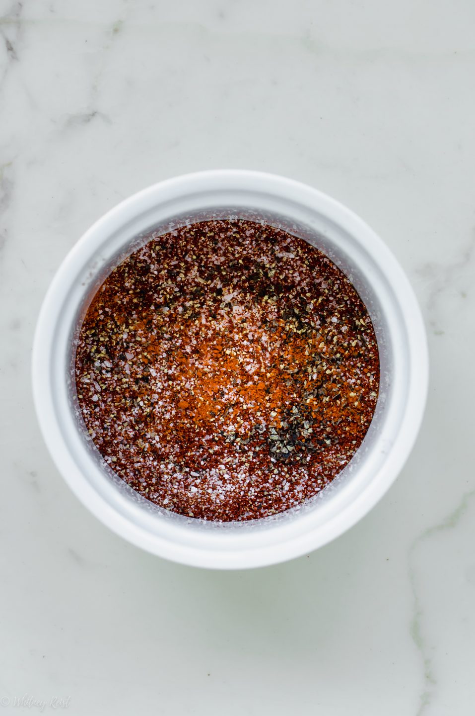 A small white bowl filled with a homemade seasoning blend for roasting okra.