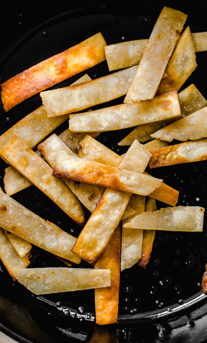 Fried tortillas strips in a cast iron skillet. 