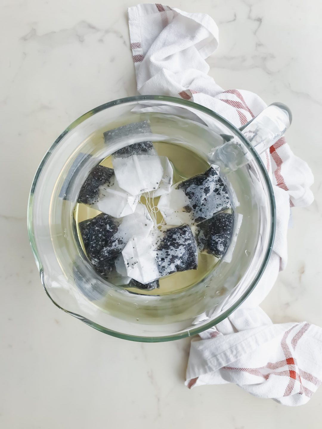 A glass pitcher filled with water and tea bags. 