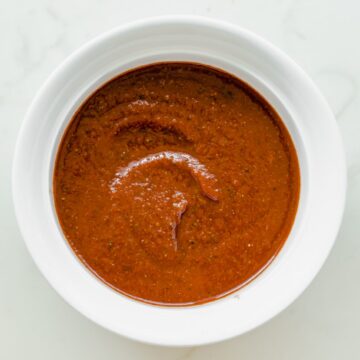 Overhead shot of a while bowl filled with easy homemade taco sauce on a marble surface.