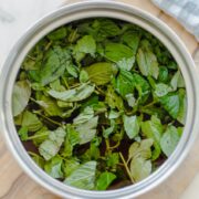 A bunch of fresh chopped mint in a saucepan filled with simple syrup.
