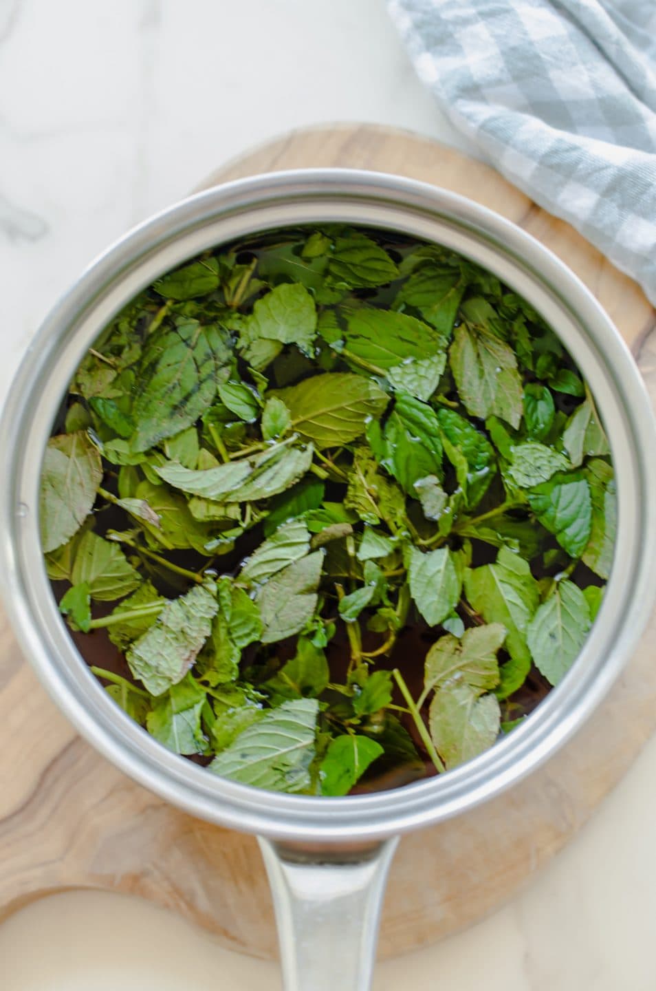 A bunch of fresh chopped mint in a saucepan filled with simple syrup.