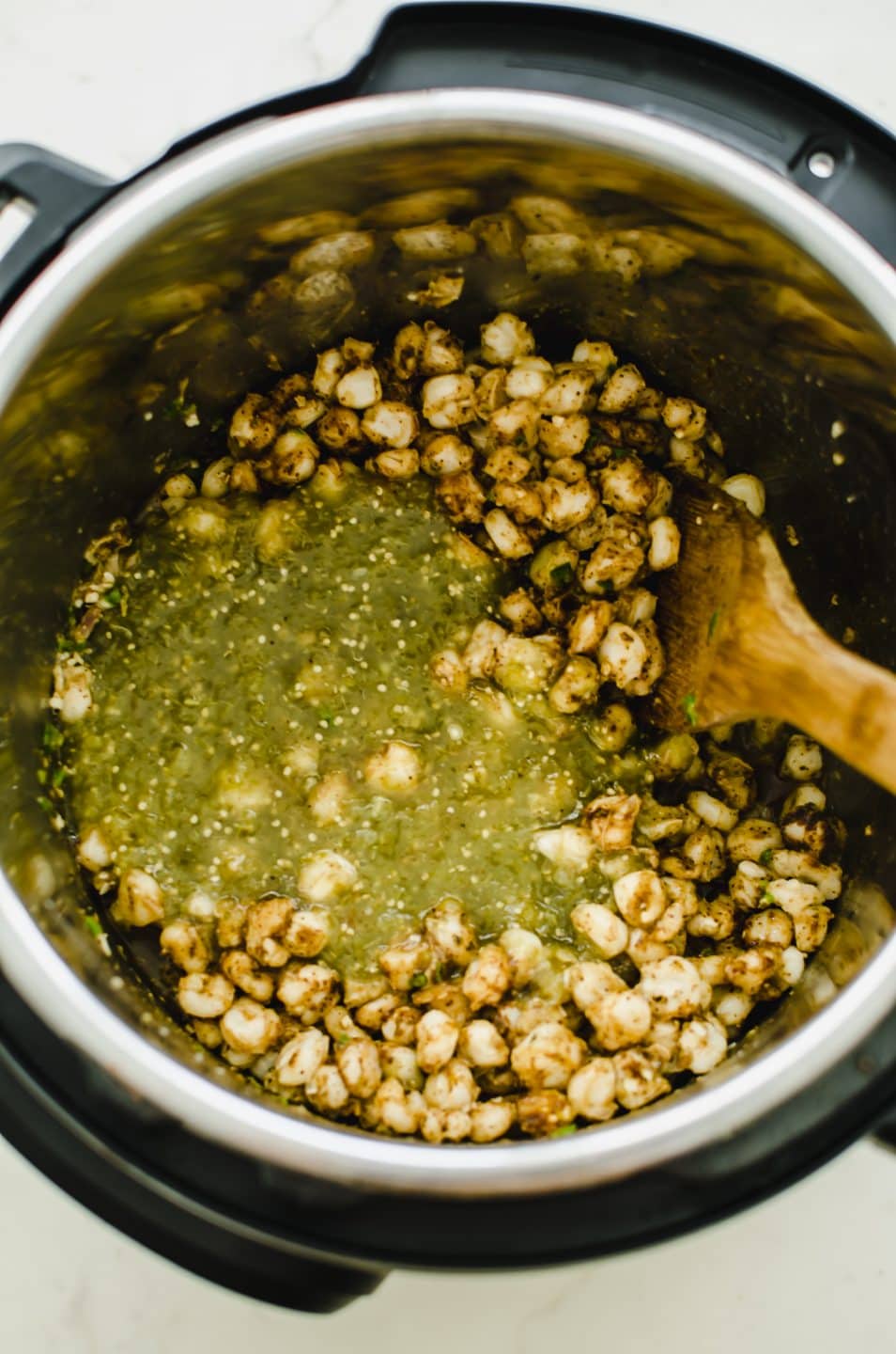 An Instant Pot filled with hominy and green salsa verde.