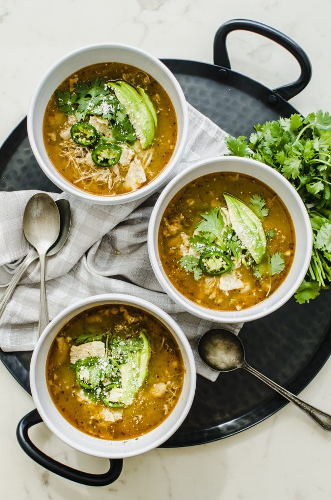 An overhead shot of three white bowls filled with soup on a cast iron platter.