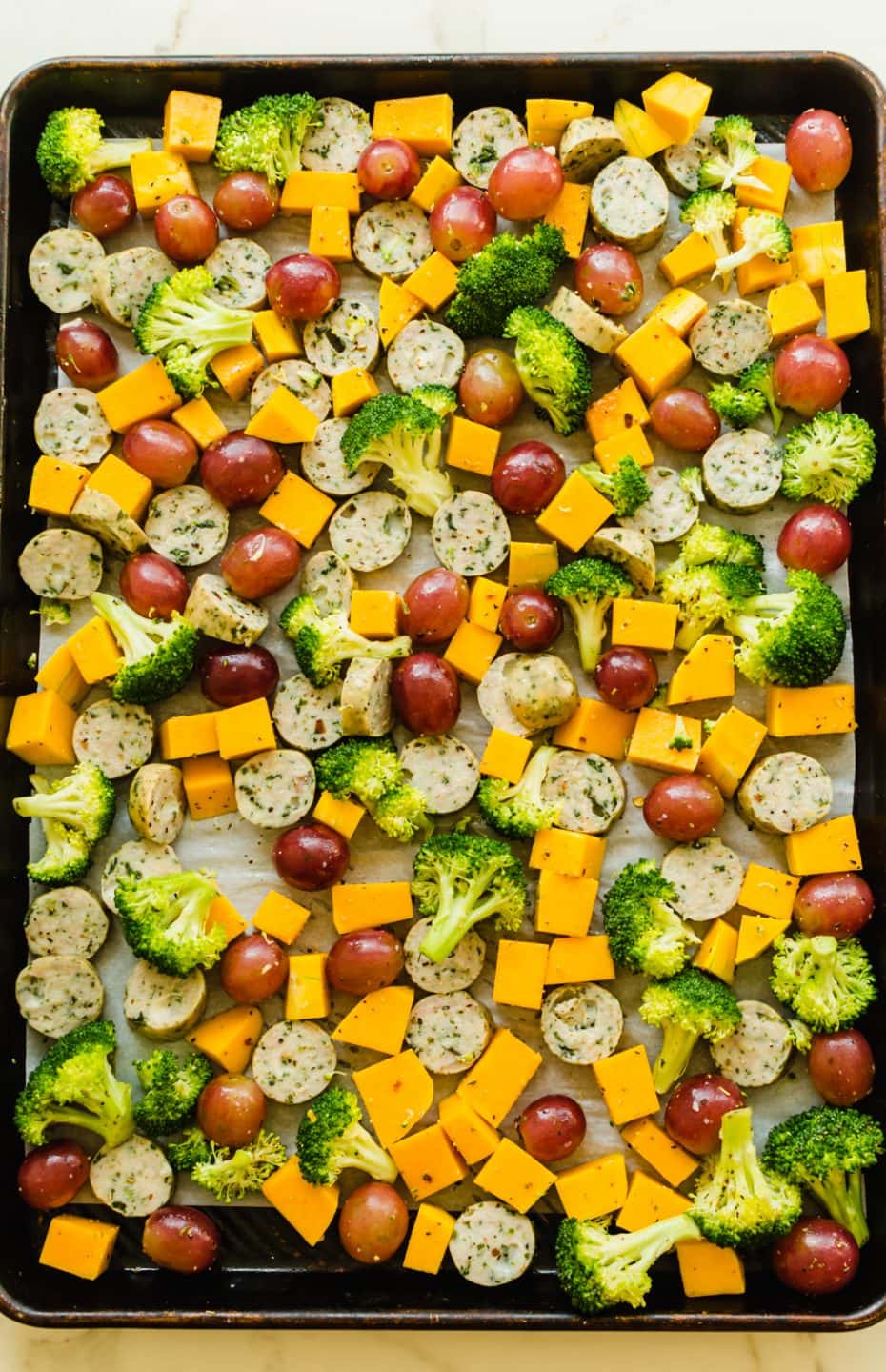 A sheet pan filled with cut veggies ready for roasting.