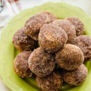 A green plate stacked with apple cider donut holes.