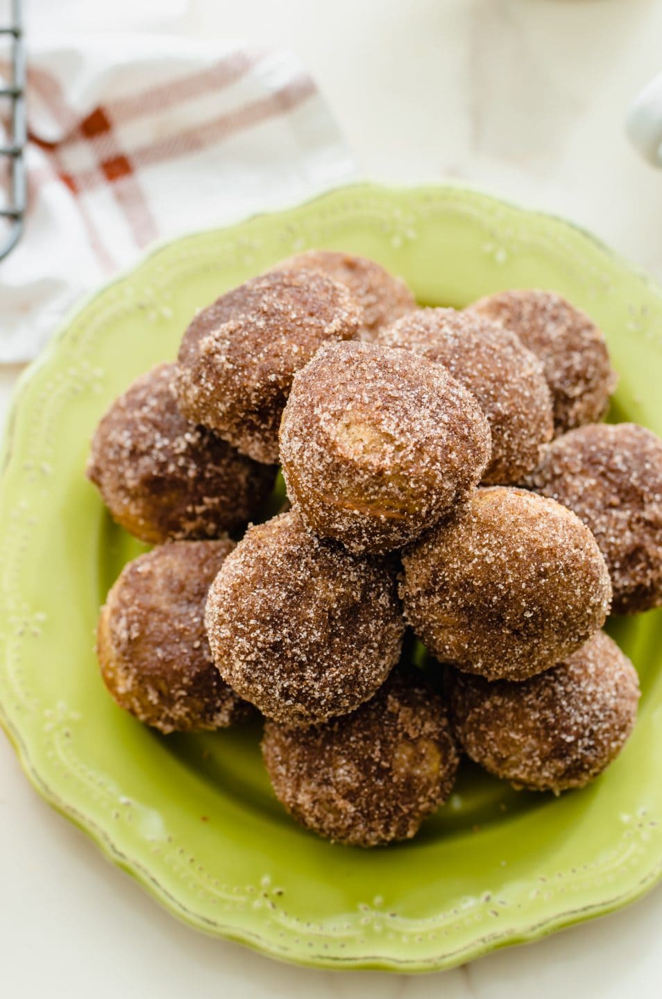 A green plate stacked with apple cider donut holes.
