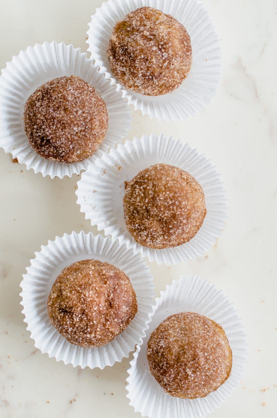 White paper muffin liners filled with apple cider donut holes.