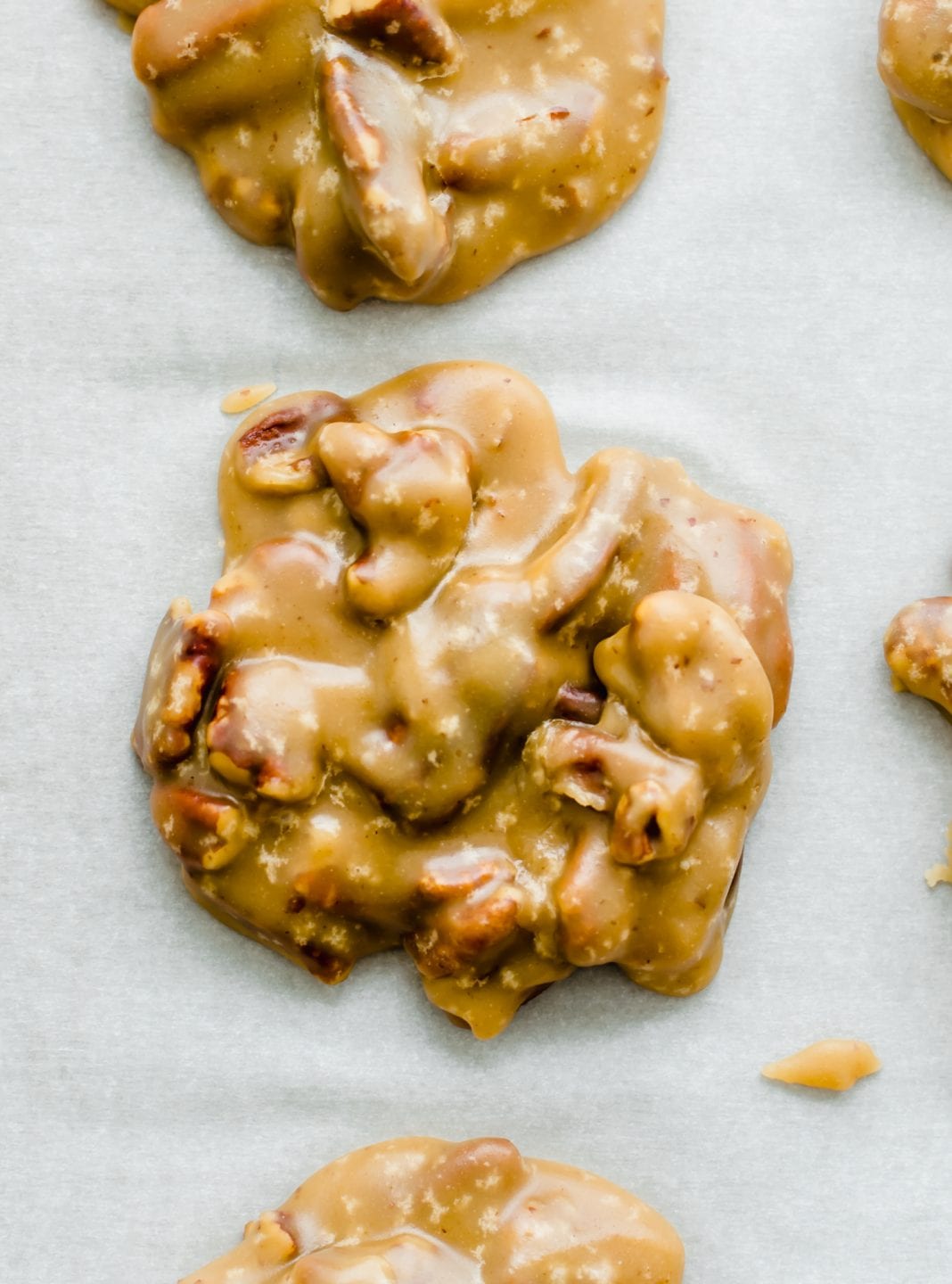 An overhead shot of a pecan praline candy drying on parchment paper.