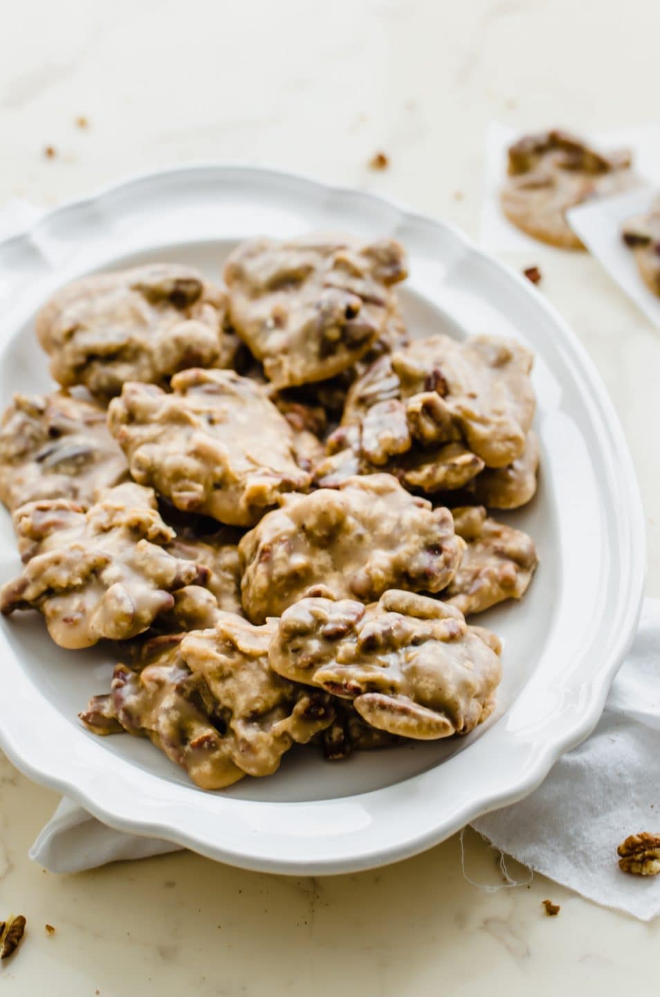 A white plate filled with boiled cider pecan praline candies on a marble countertop.