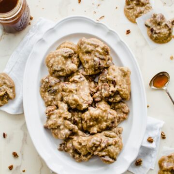 A white plate filled with boiled cider pecan praline candies on a marble countertop.