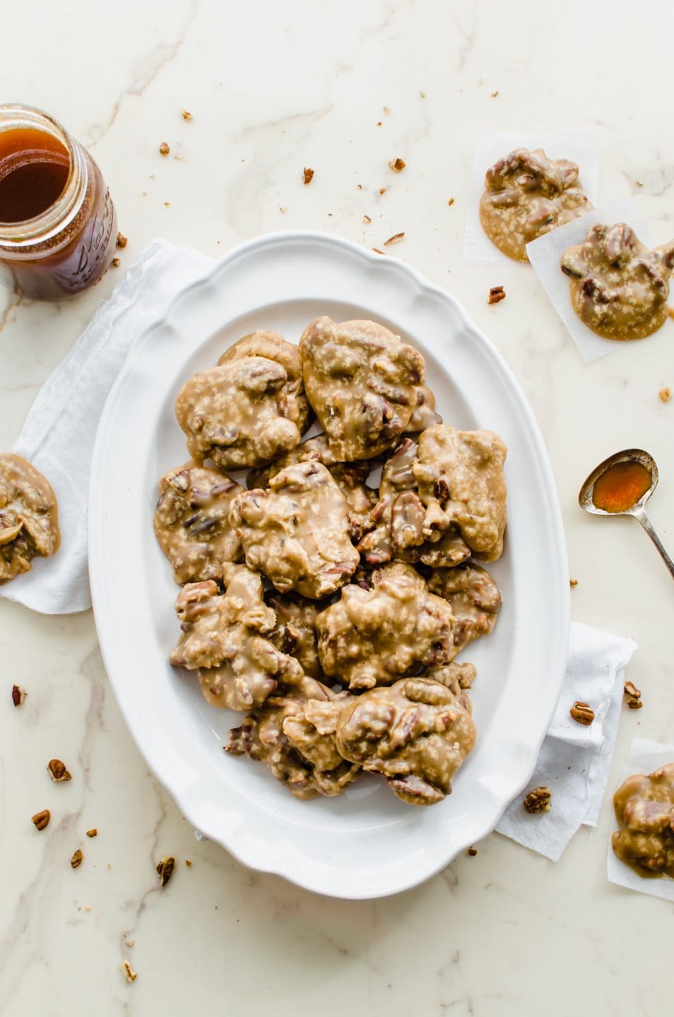 A white plate filled with boiled cider pecan praline candies on a marble countertop.