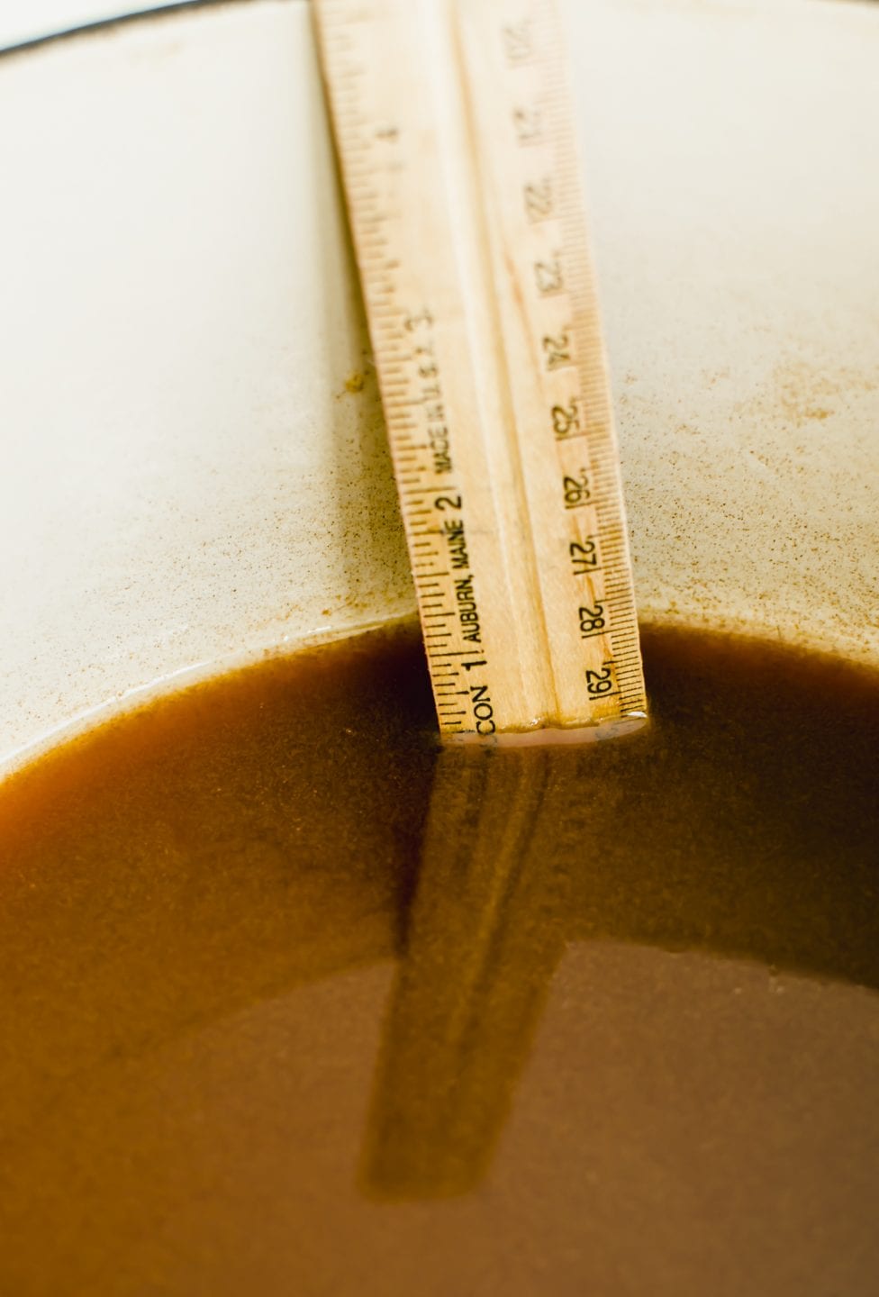 A ruler indicating how much apple cider has reduced down in a pot.