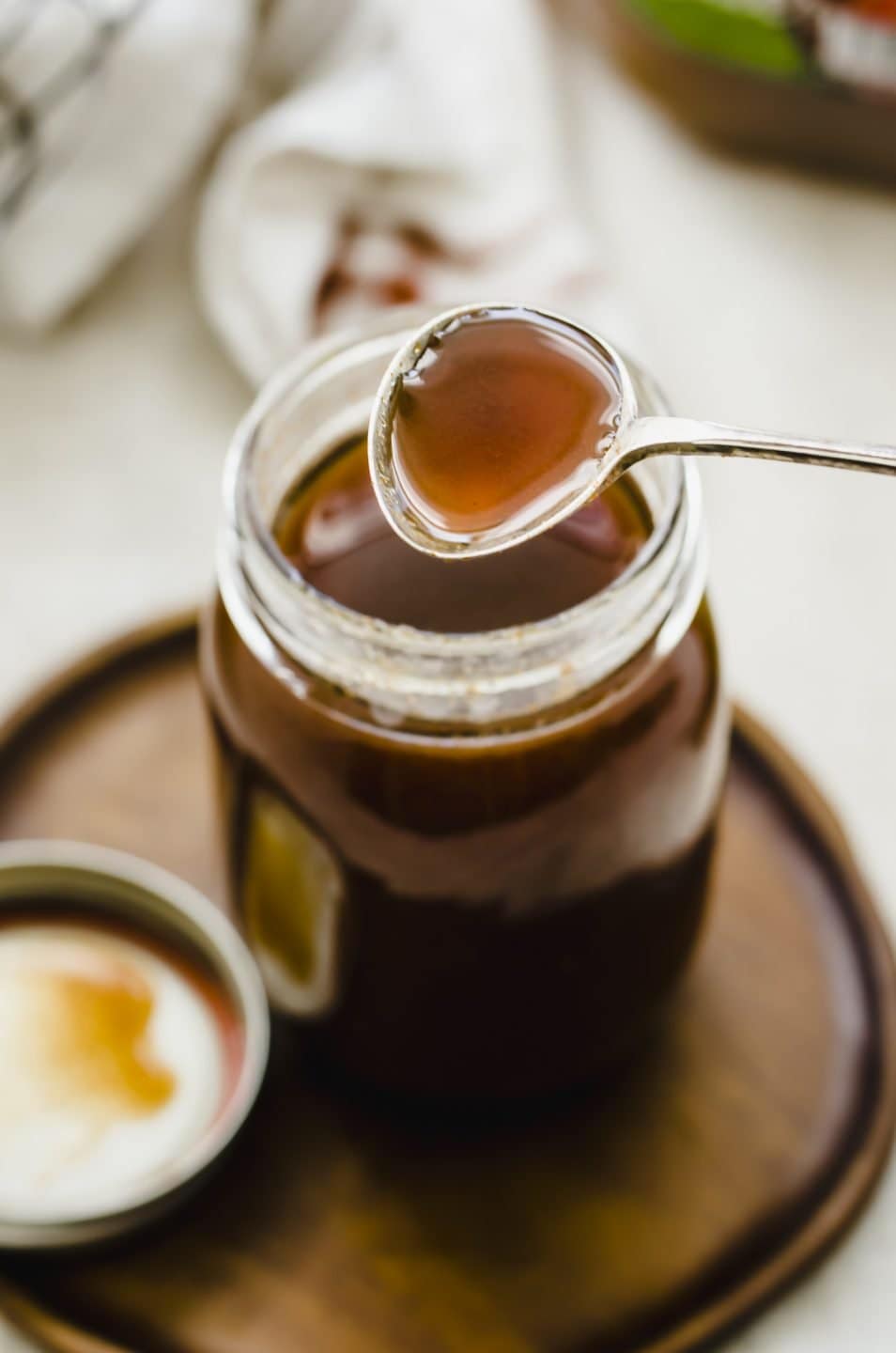 A spoon removing some boiled apple cider syrup from a jar. 