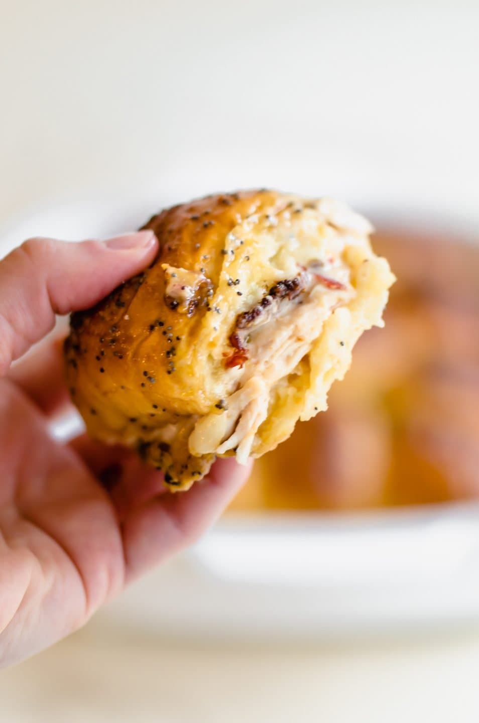 a hand holding a Kentucky Hot Brown Slider with a bite taken out of it.