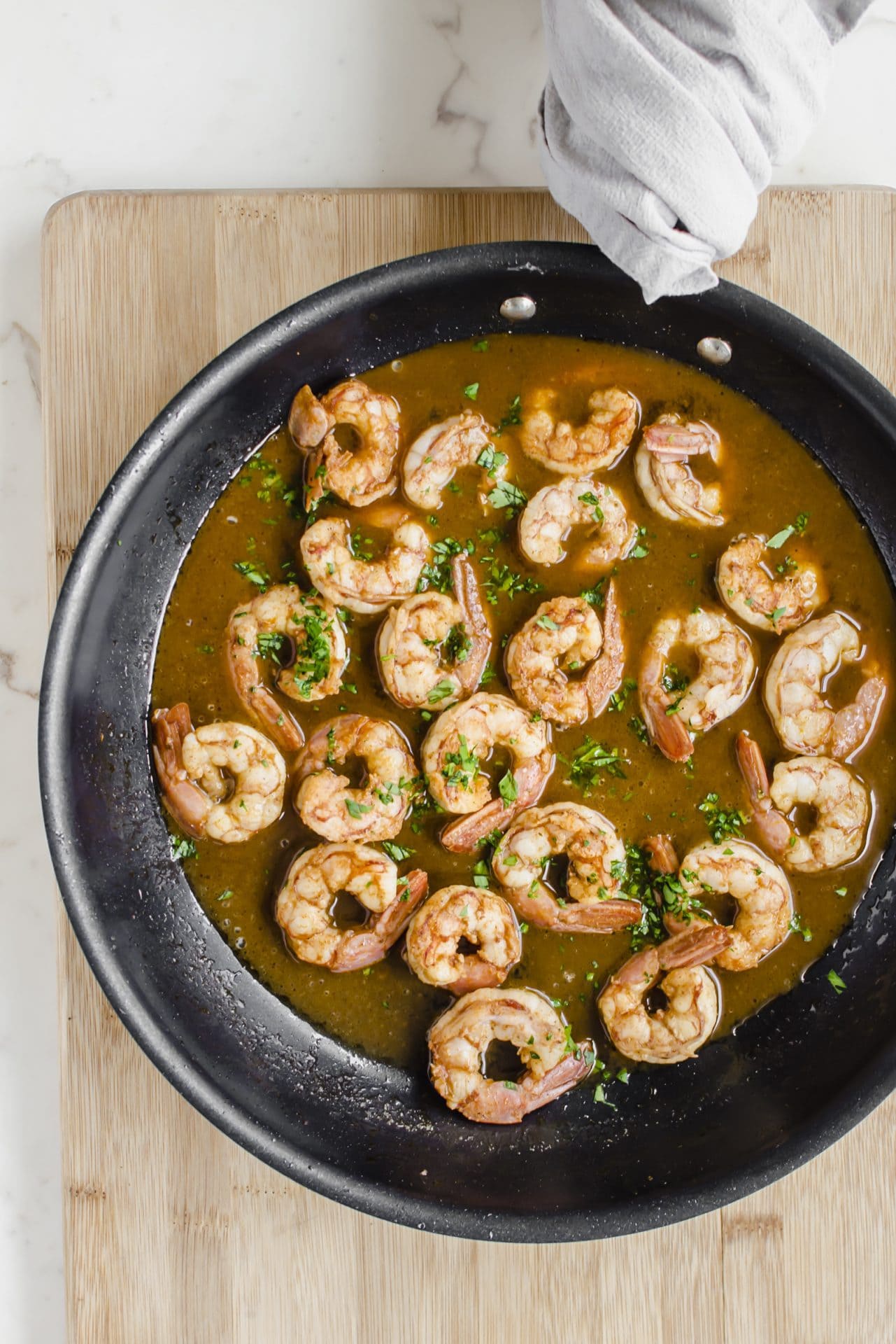 An overhead shot of a large skillet with shrimp and sauce inside of it. 