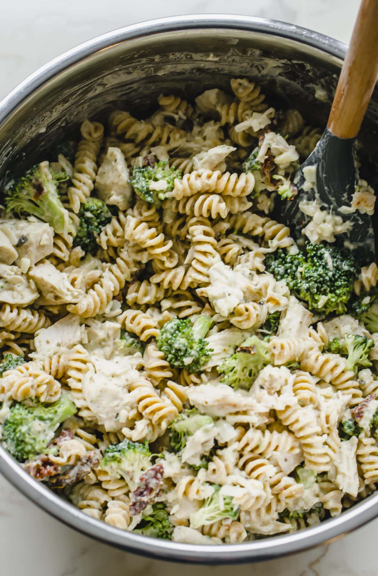 A bowl with all of the ingredients for Chicken Rotini Bake being tossed together.