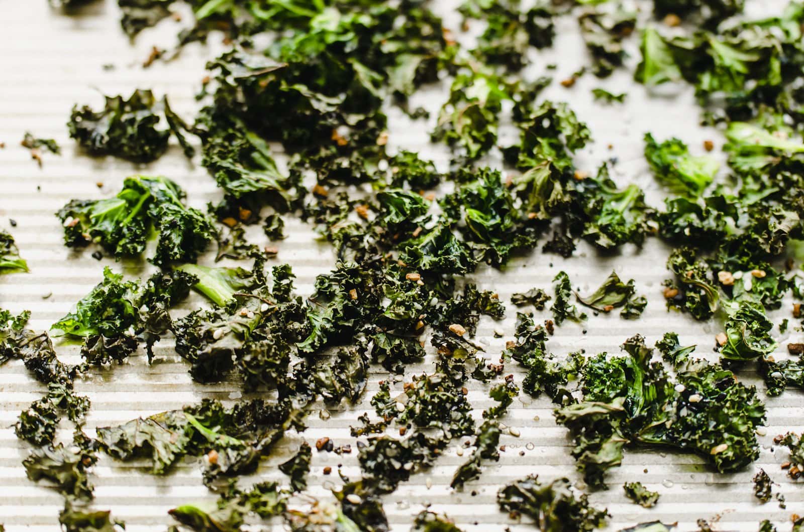 A close-up shot of baked kale chips on a baking sheet.