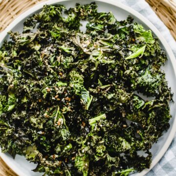 A blue plate of kale chips on a gingham dish towel.