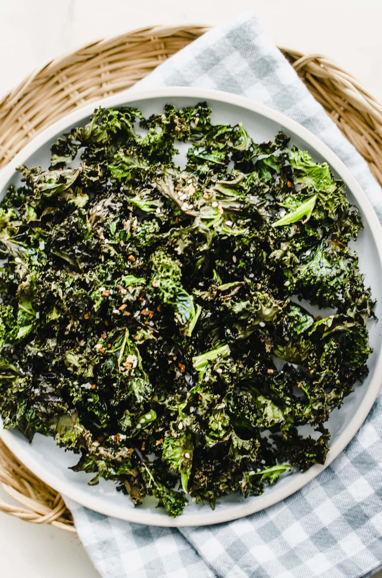 A blue plate of kale chips on a gingham dish towel. 