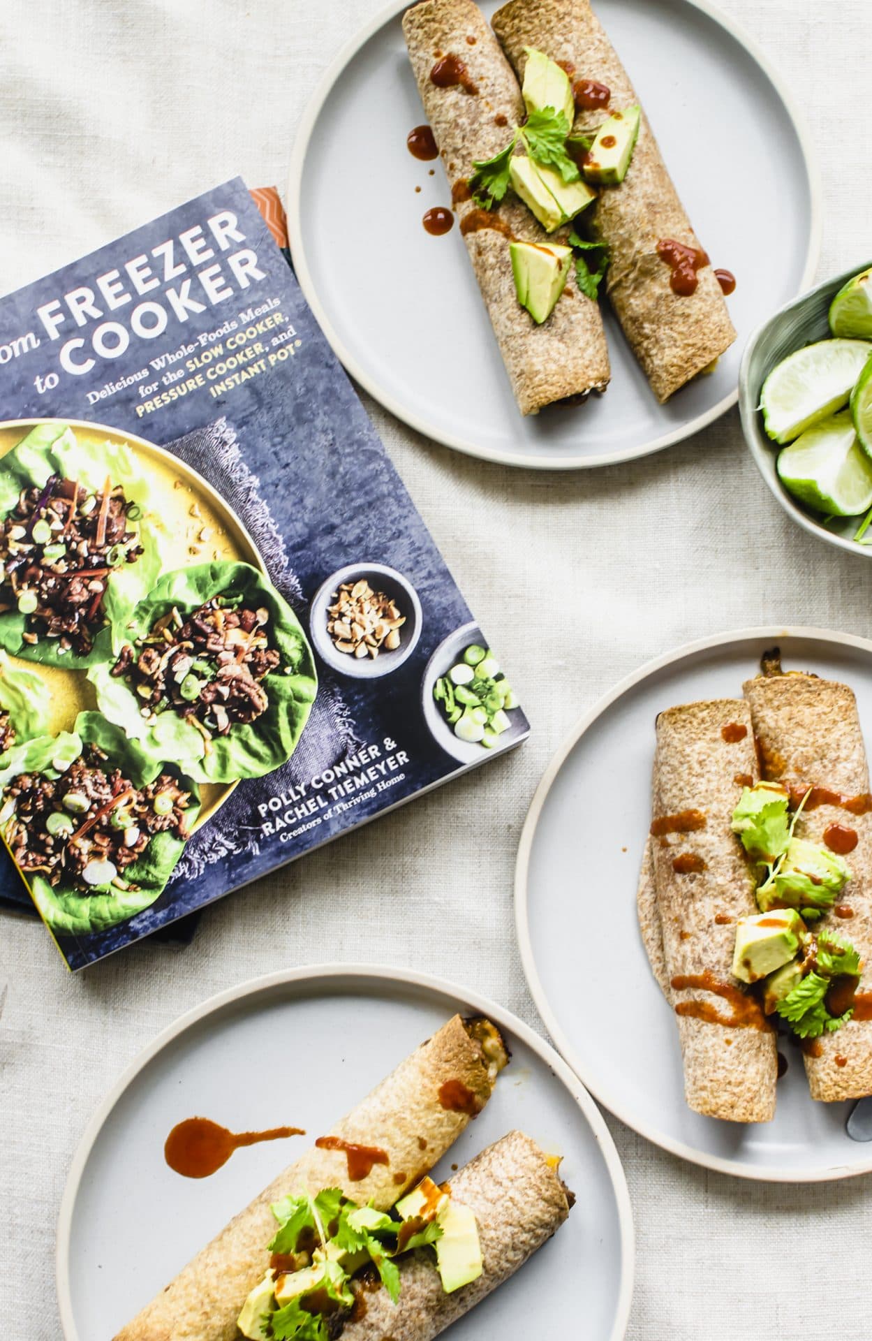 From Freezer to Cooker cookbook on a counter with blue plates filled with taquitos. 