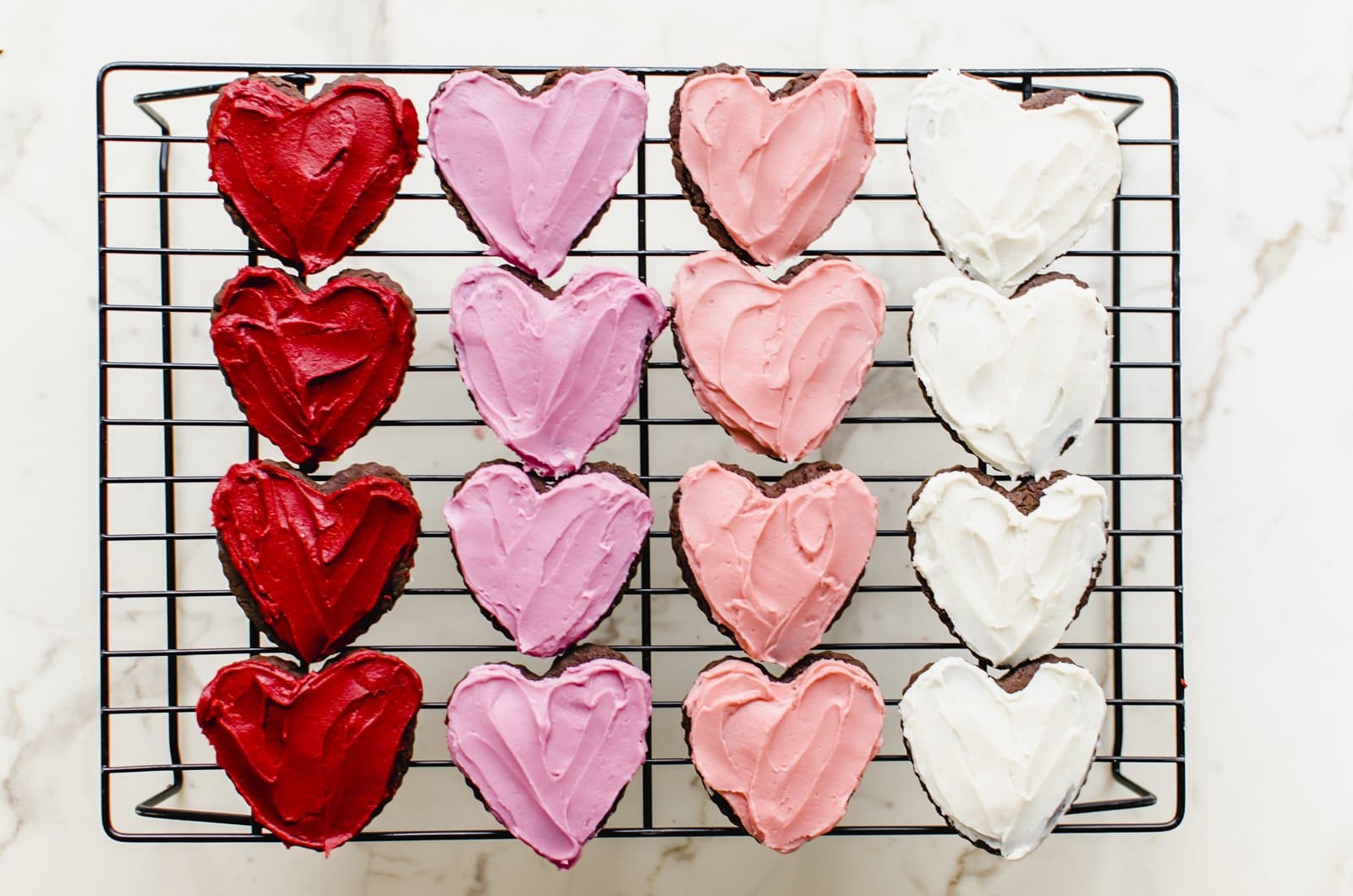 Rose of red, pink, peach and white frosted cutout cookies on a wire baking rack.