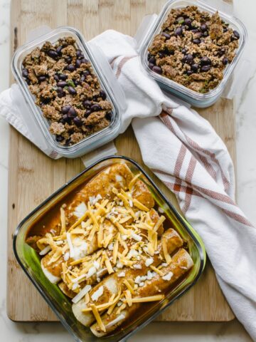 A freezer container filled with enchiladas and two meal prep containers with enchilada filling.