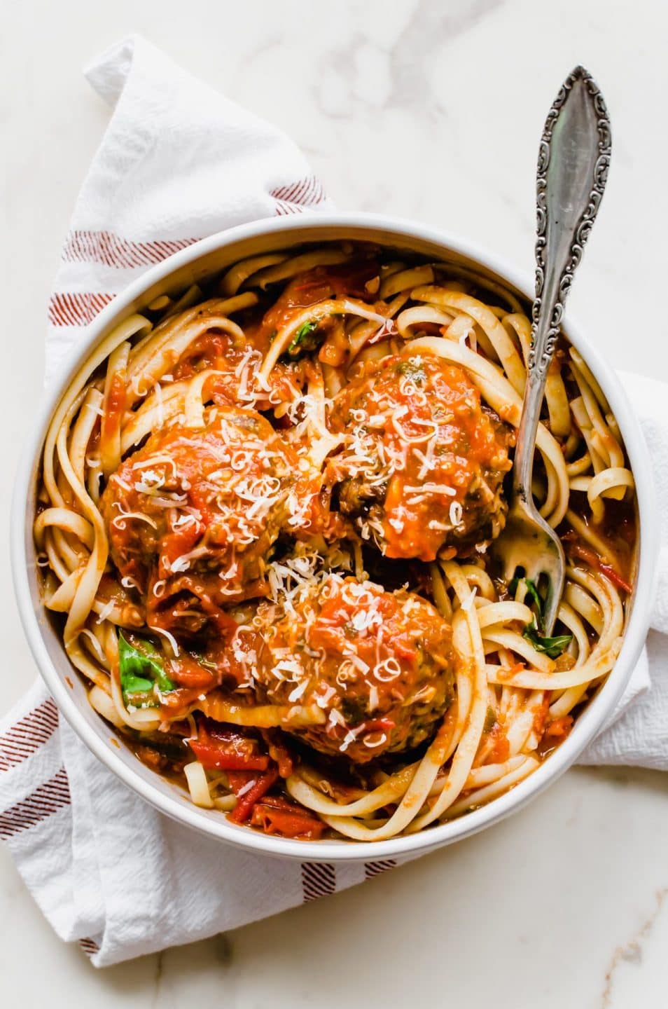 A bowl of spaghetti and meatballs with a fork on the side. 
