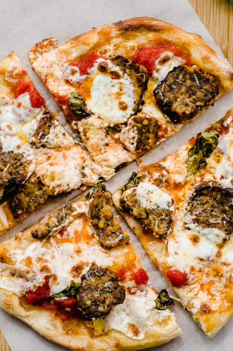 A sliced meatball pizza on a piece of parchment paper. 