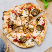 Overhead shot of a baked meatball pizza on a sheet of parchment paper.