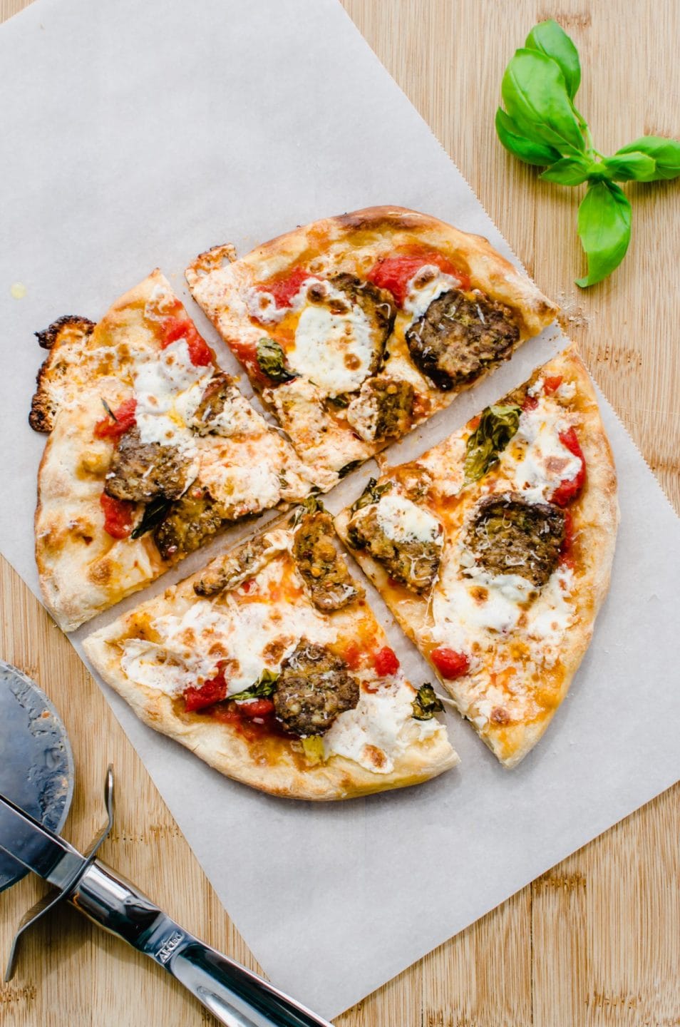 Overhead shot of a baked meatball pizza on a sheet of parchment paper. 