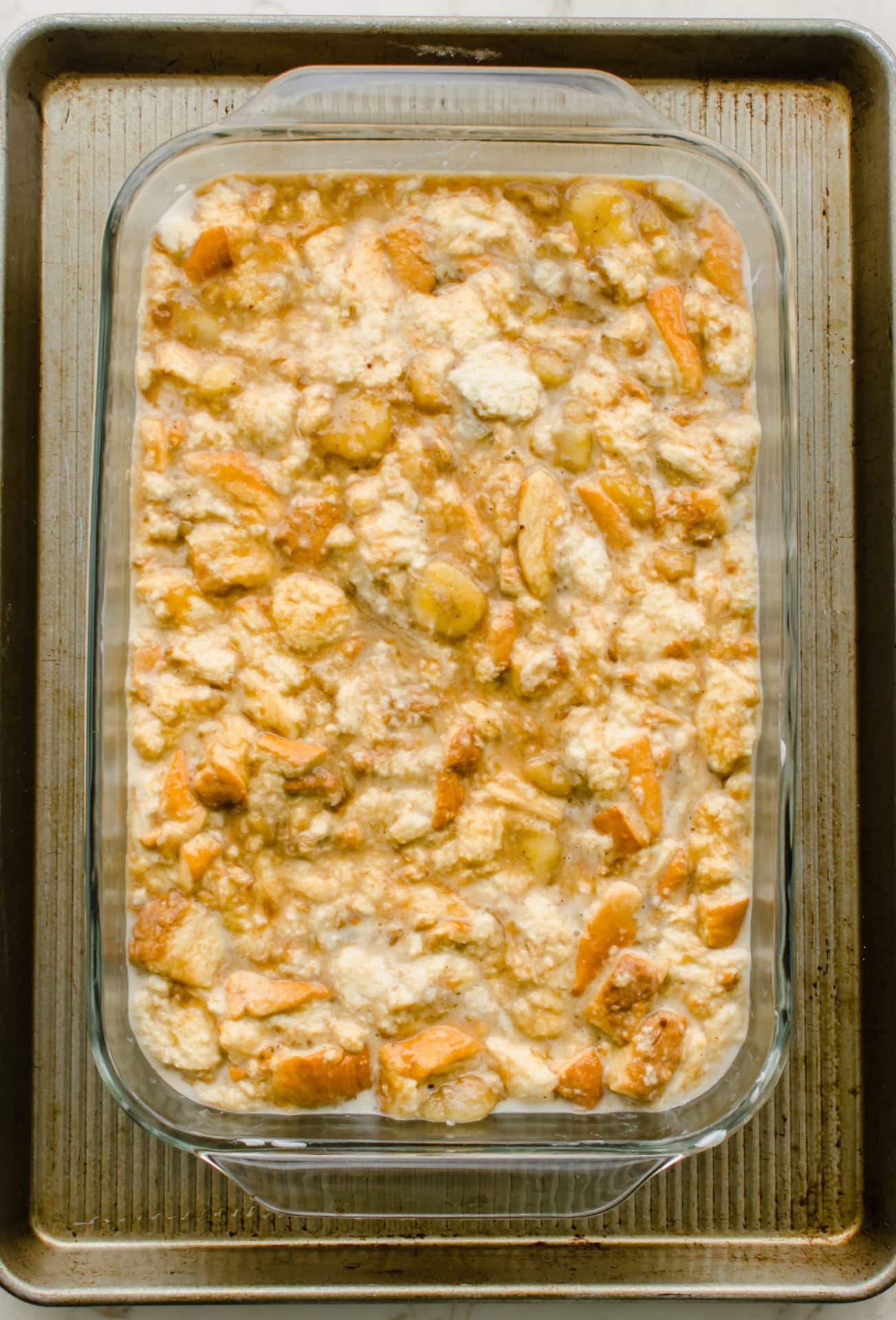 Unbaked bread pudding in a glass baking dish.