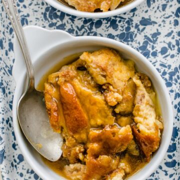 Bread pudding in white dishes on a speckled blue tray.