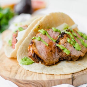 Photo of two pork tacos with avocado dressing.