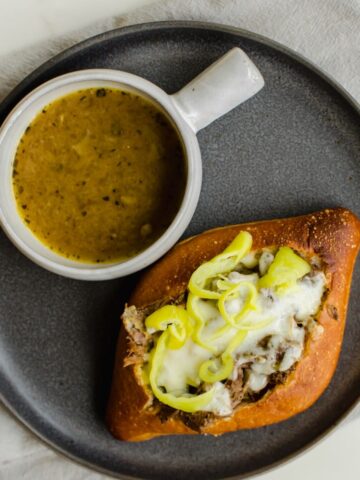 Overhead photo of an Italian beef sub and a cup of dipping au jus.