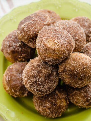 A green plate piled high with apple cinnamon donut holes.