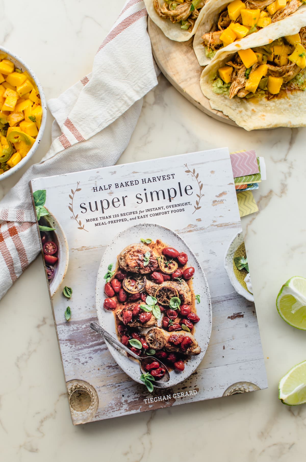 The Half Baked Harvest Super Simple cookbook on a white marble counter. 