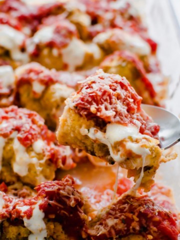 Glass cooking dish with roasted cauliflower topped with tomato sauce and melted mozzarella cheese.