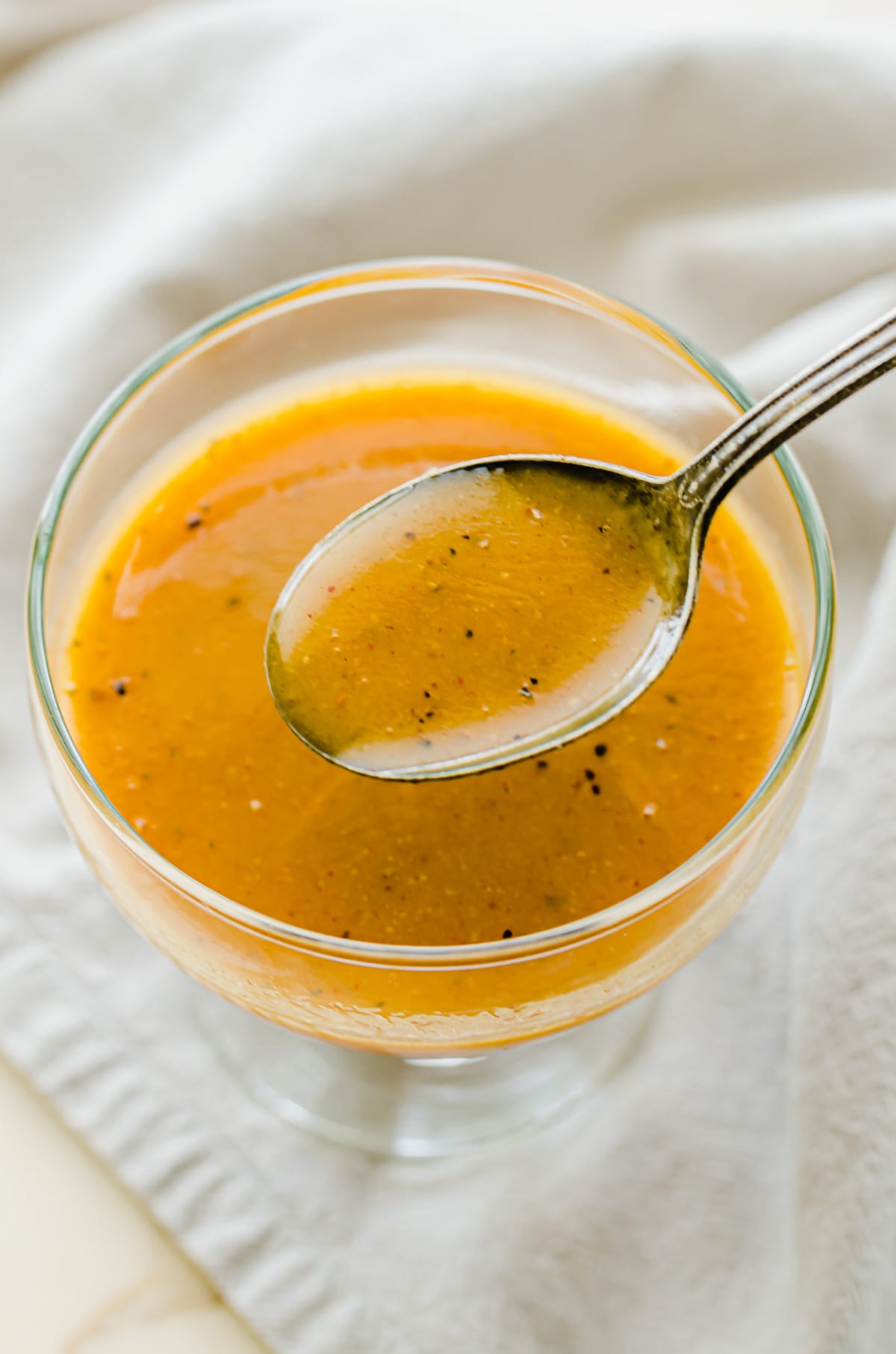 A clear glass bowl filled with honey mustard dressing. 