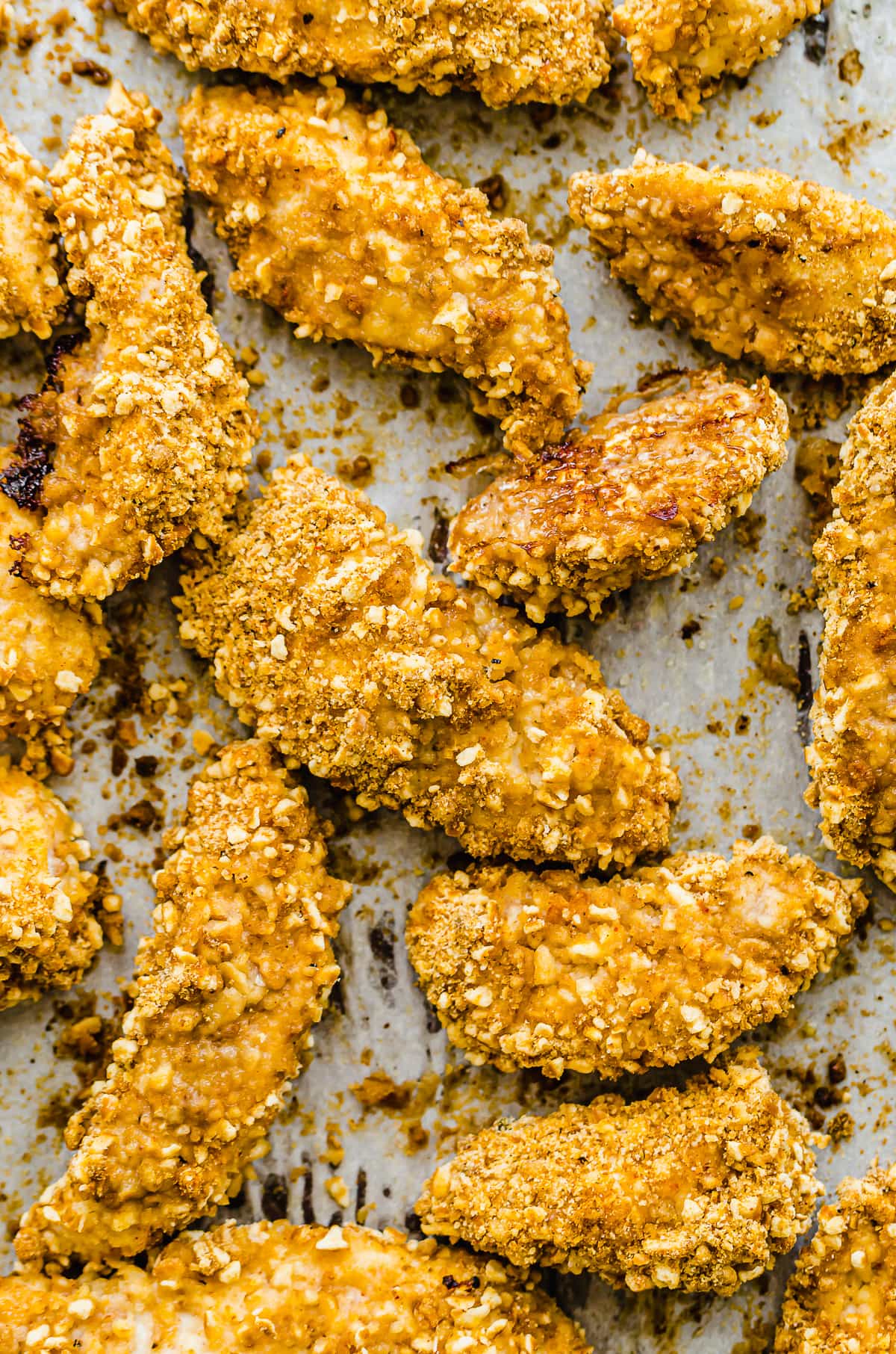 A close up shot of crispy pretzel chicken on a baking sheet.