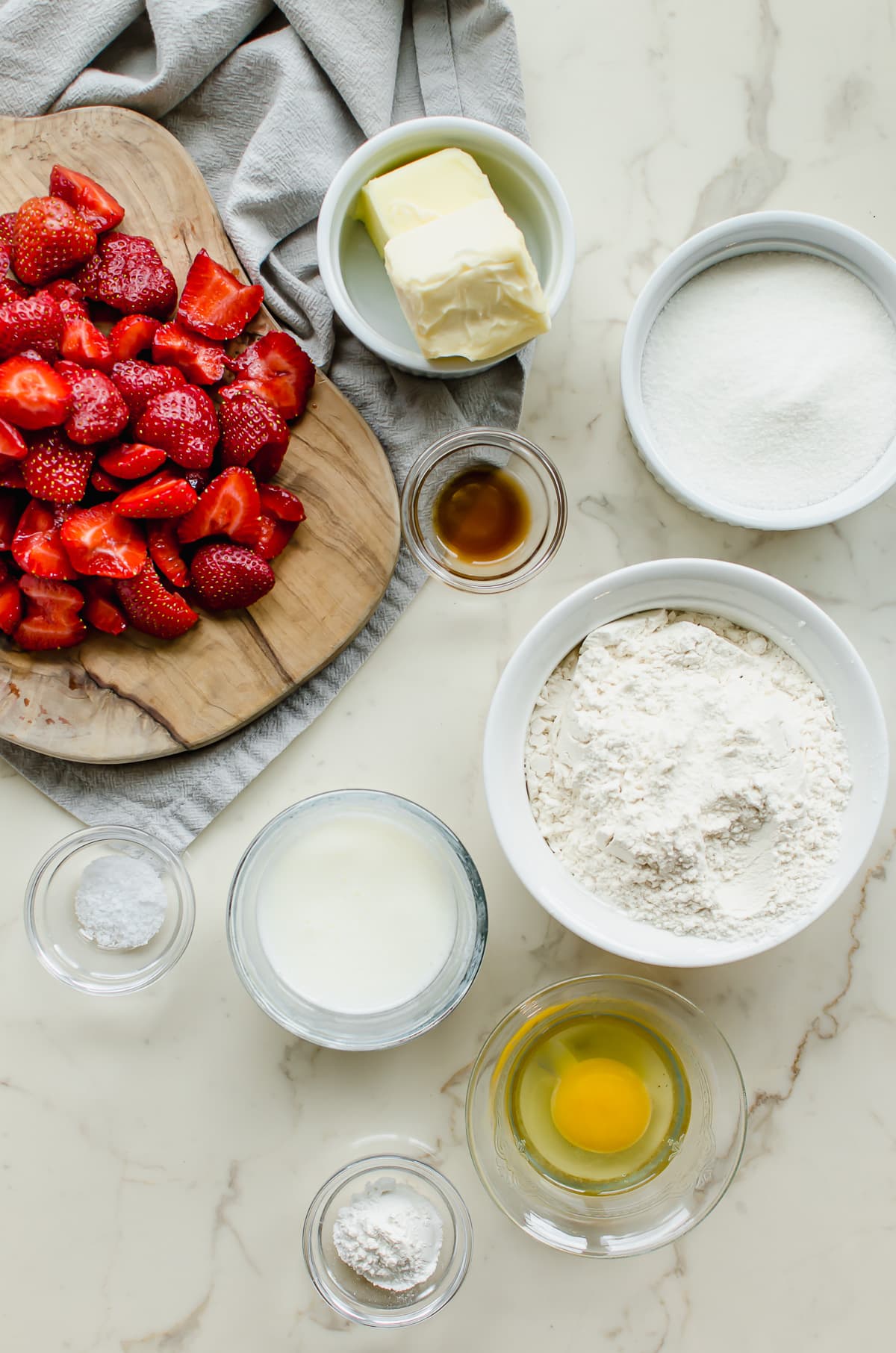 Measured ingredients in white bowls for making a strawberry buttermilk cake.