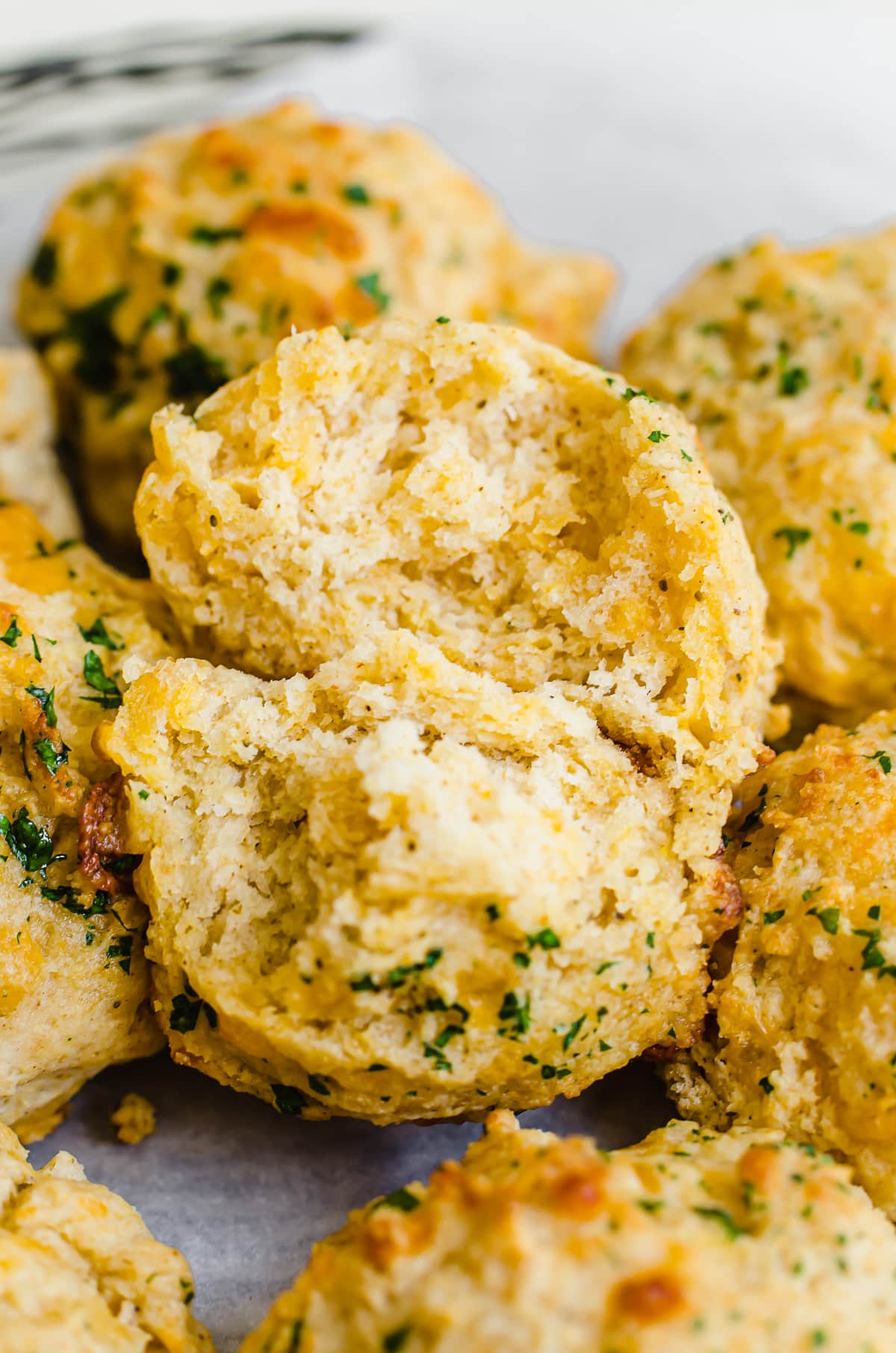 A spilt open cheddar bay biscuit on a platter of biscuits.