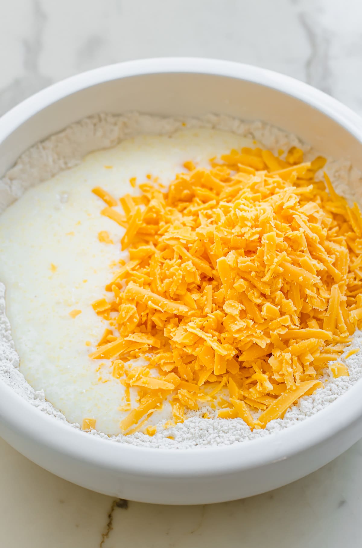 Cheese and buttermilk being mixed into flour.