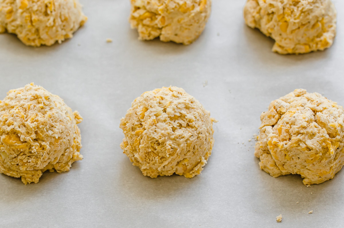 Unbaked cheddar bay biscuits on a baking sheet.