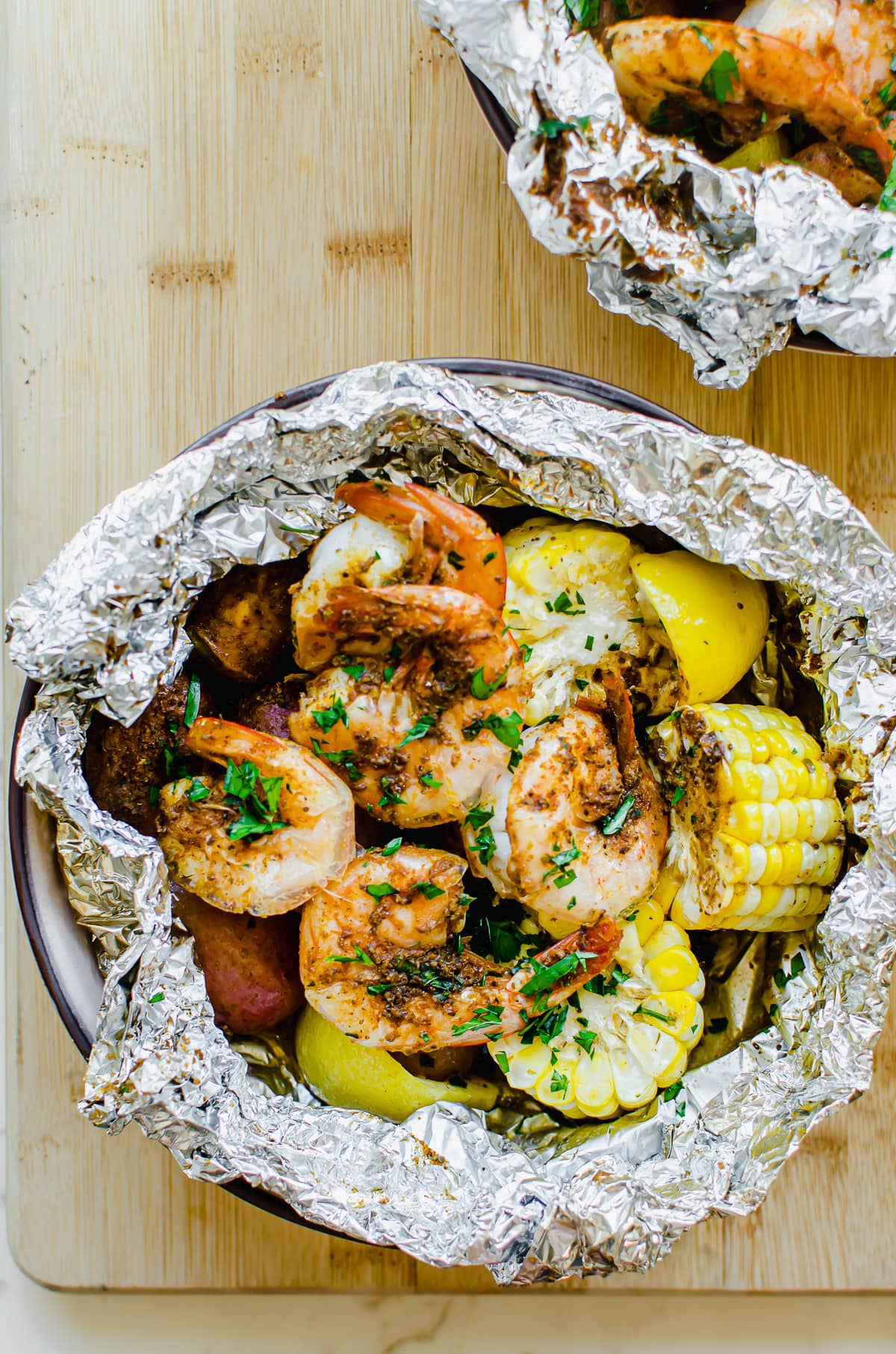 A close-up overhead shot of a foil packet with shrimp boil ingredients.