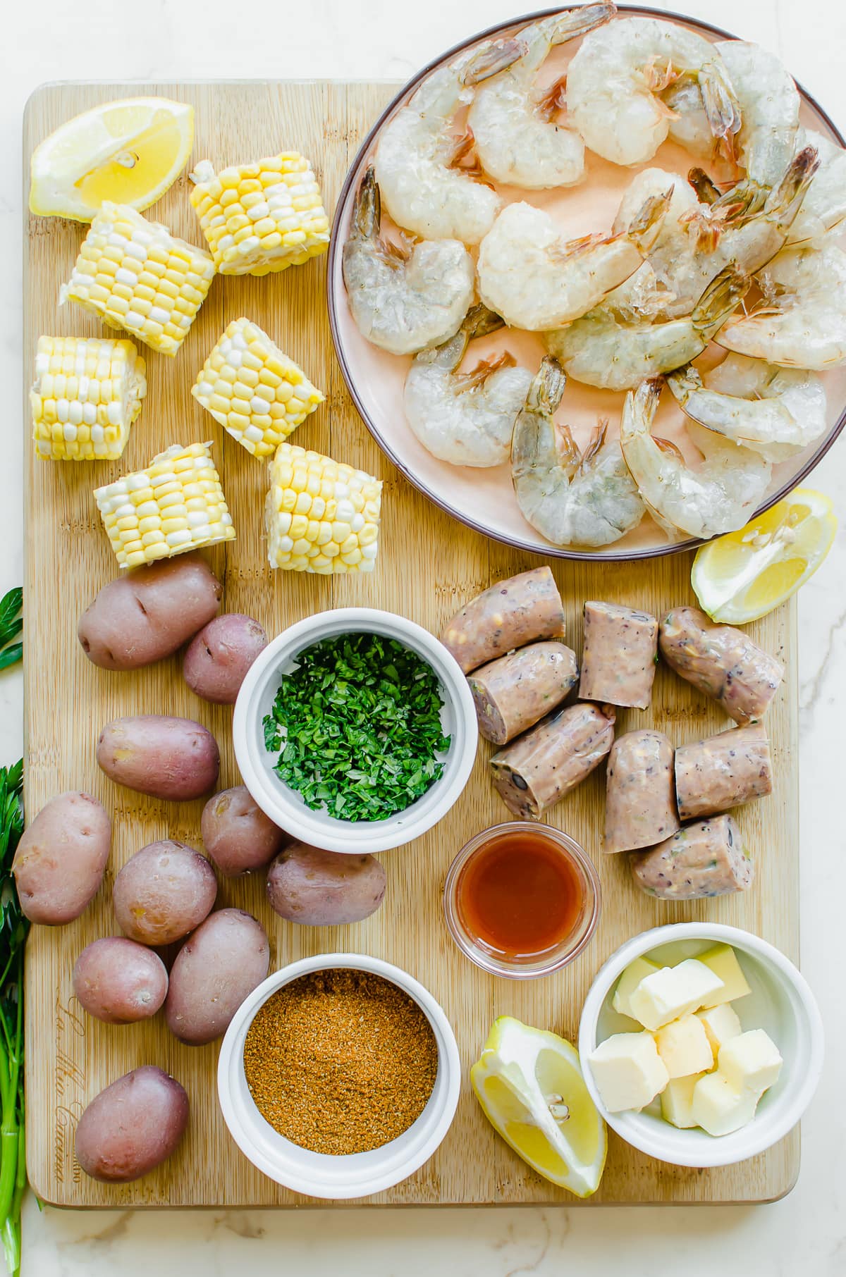 Measured ingredients on a cutting board for a seafood boil.