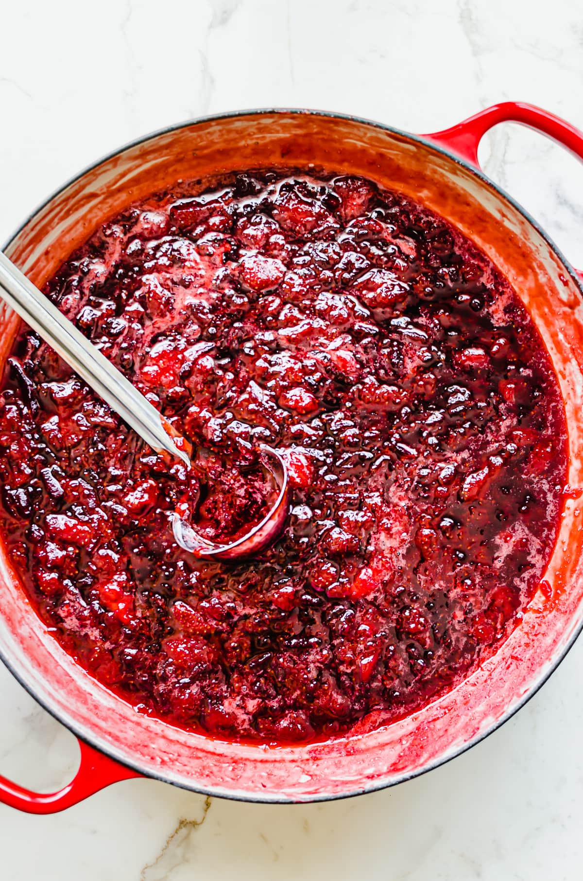 A large red braiser filled with strawberry jam.